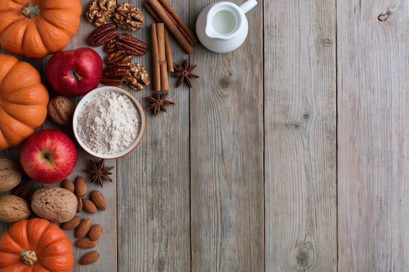 Autumn baking ingredients arranged along left edge of rustic wooden table