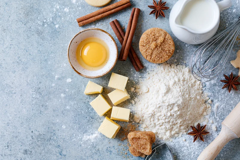 Baking ingredients arranged on a flour-dusted countertop with copyspace