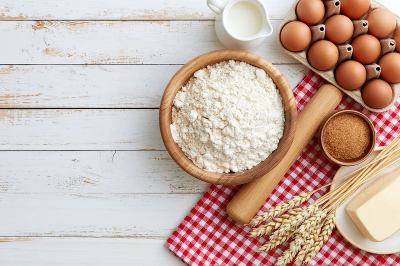 Baking ingredients arranged on a white wooden table with copyspace