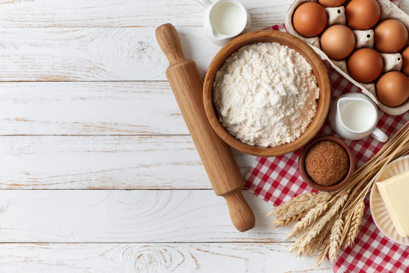 Baking ingredients arranged on a white wooden table with copyspace