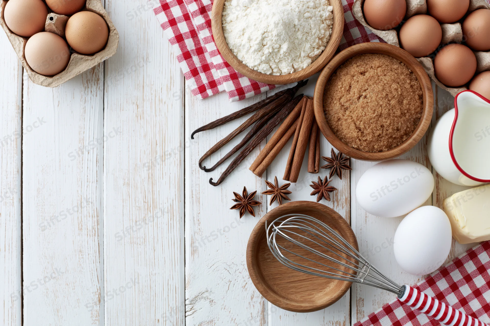 Baking ingredients arranged on a white wooden tabletop with copyspace on the left