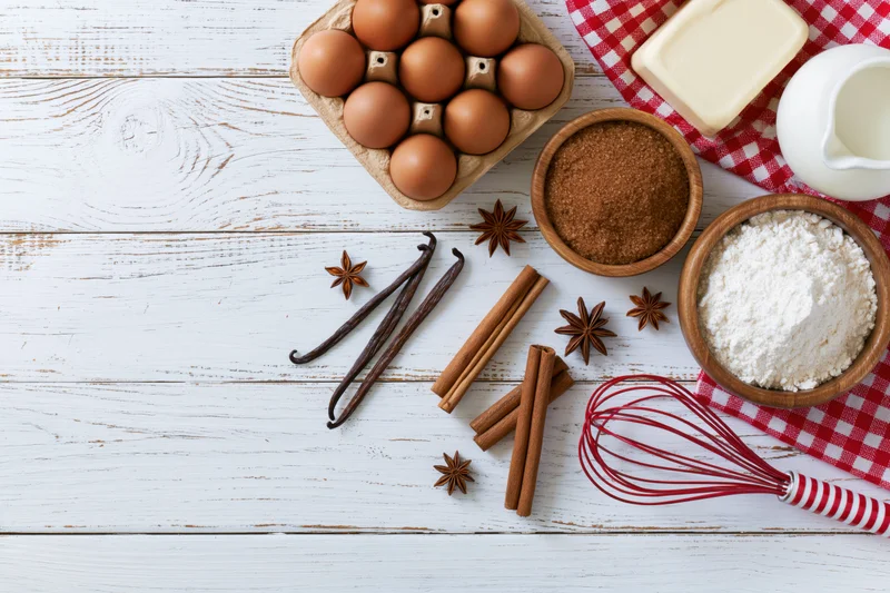 Baking ingredients arranged on white wooden table with copyspace on left