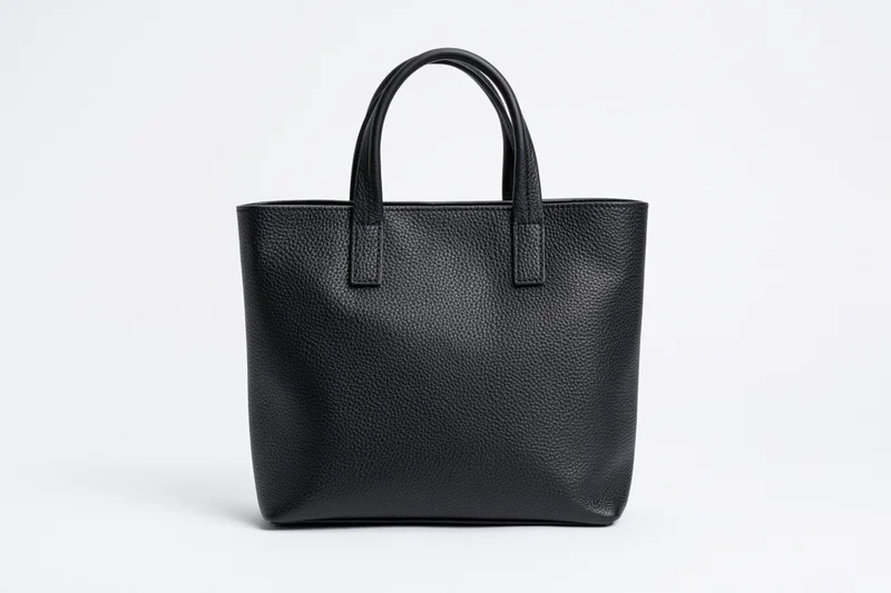 Black pebbled leather tote handbag with short top handles on white background