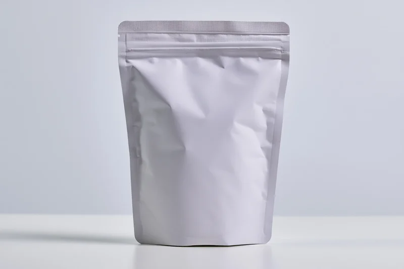 Blank white matte stand-up pouch with zipper seal upright on white surface