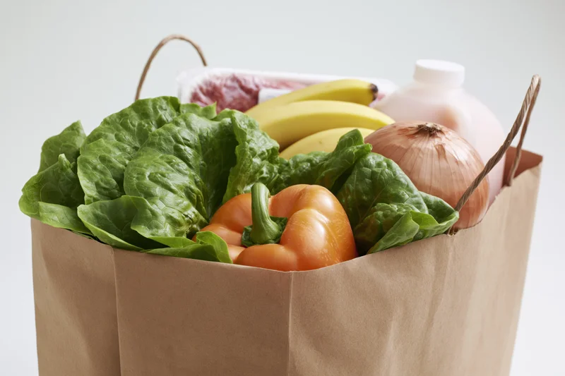Brown paper bag filled with fresh produce and dairy products for grocery shopping