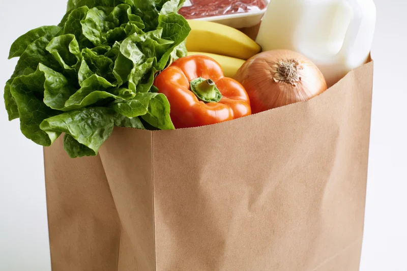Brown paper bag filled with fresh vegetables fruits and dairy products for grocery shopping
