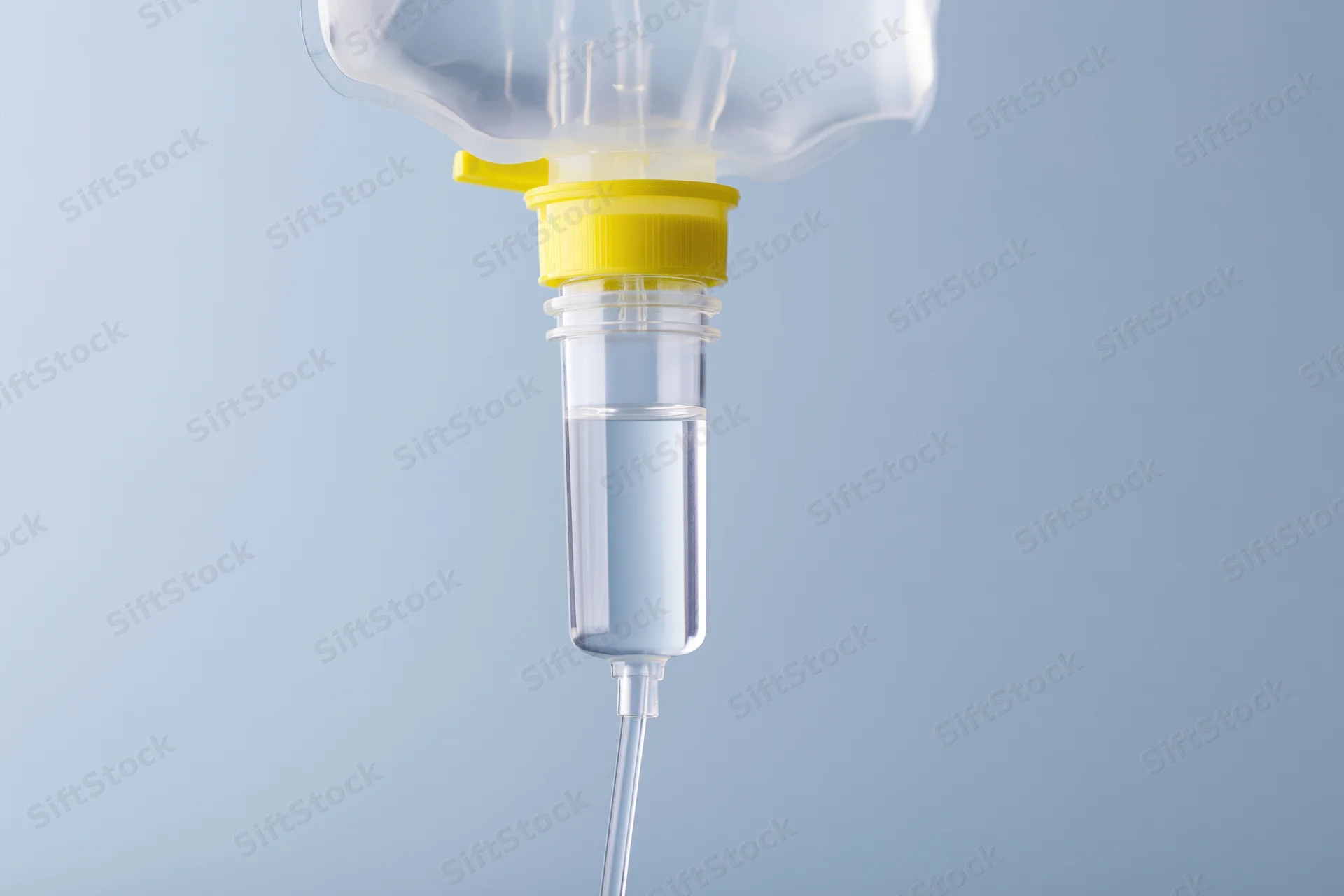 Clear iv saline bag with drip chamber and tubing against blue background