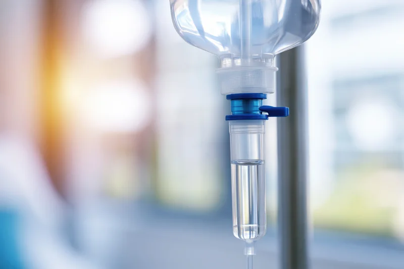 Close-up of a clear iv saline drip bag hanging on a hospital pole