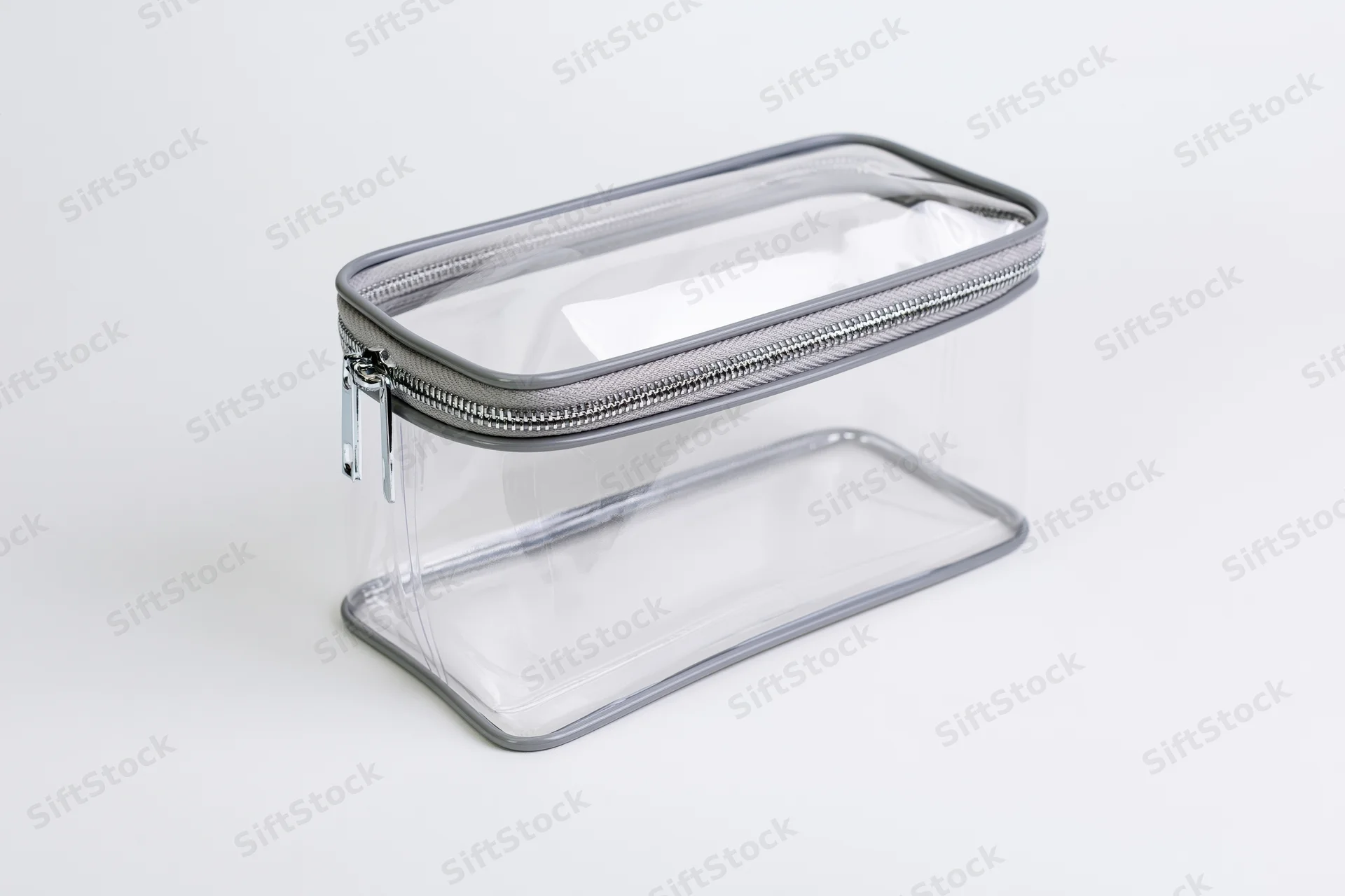 Clear transparent pvc toiletry bag with silver zipper empty on white background