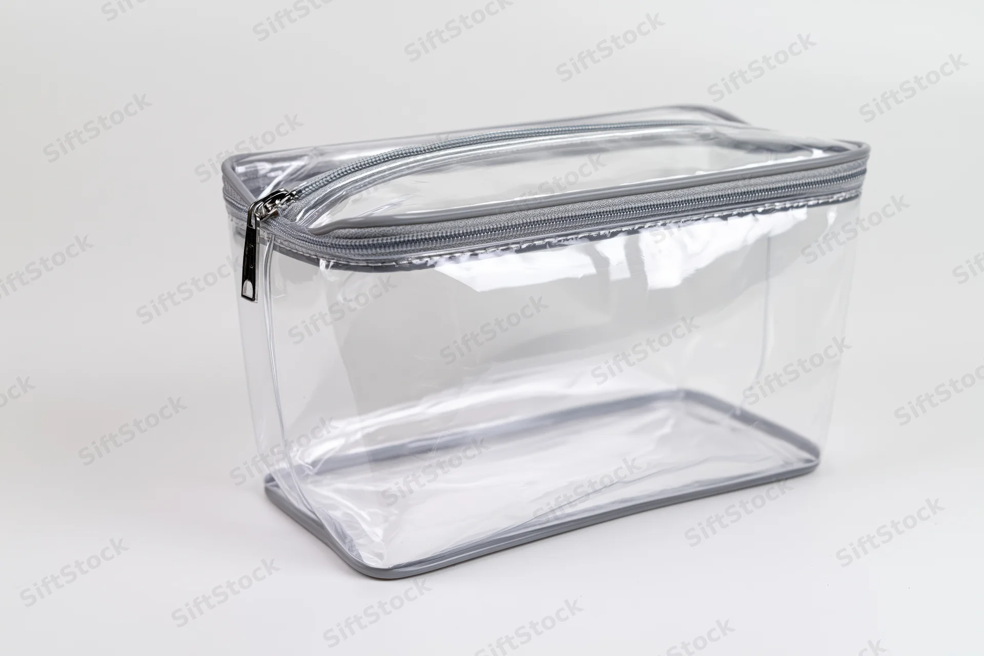 Clear transparent pvc toiletry bag with silver zipper empty on white background