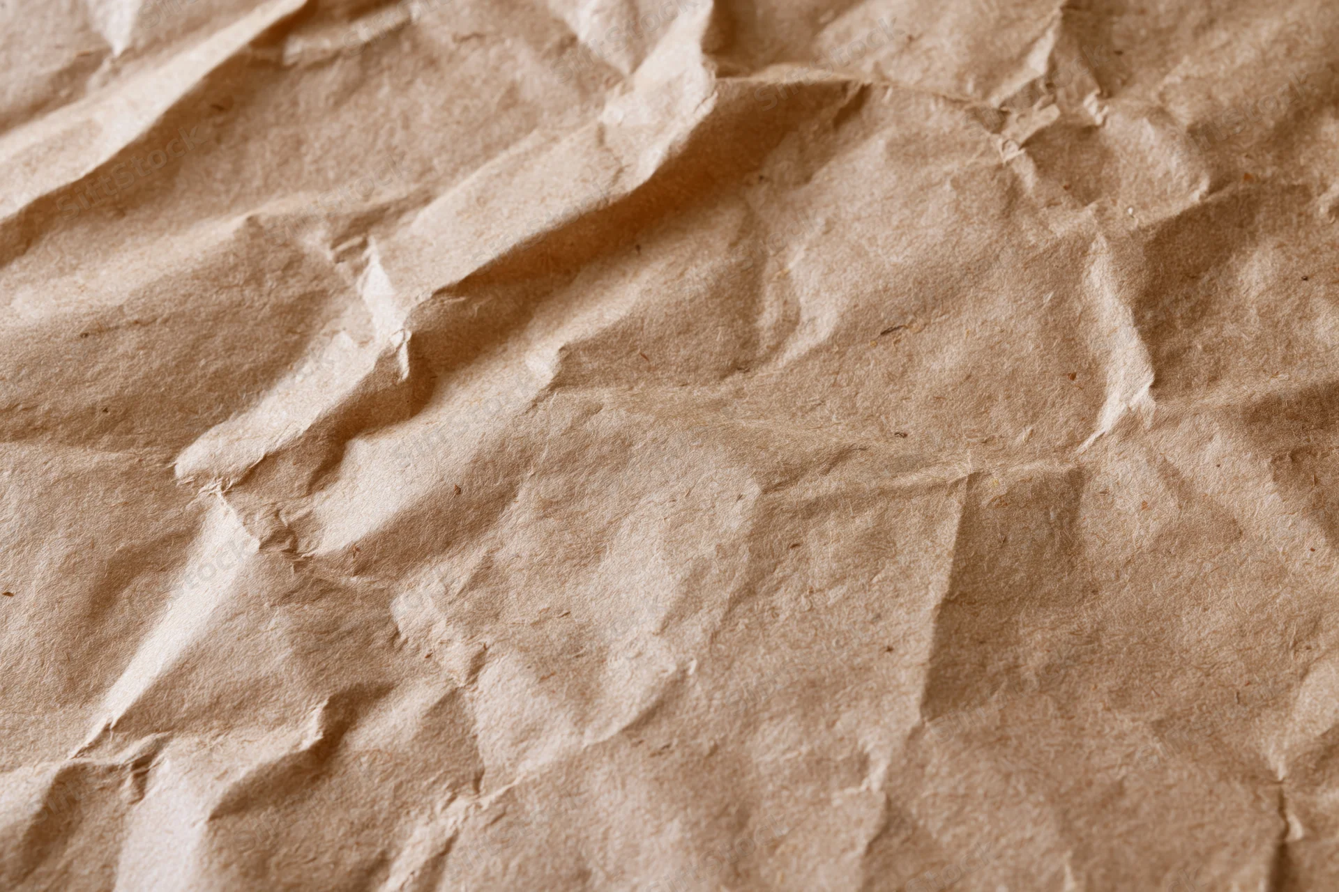 Close-up of crumpled brown kraft paper surface with natural texture and folds