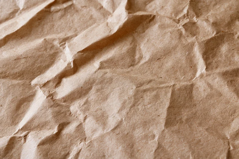 Close-up of crumpled brown kraft paper surface with natural texture and folds