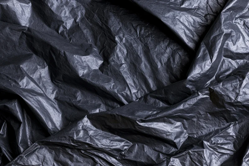 Close-up of heavily crumpled black plastic sheeting laid flat