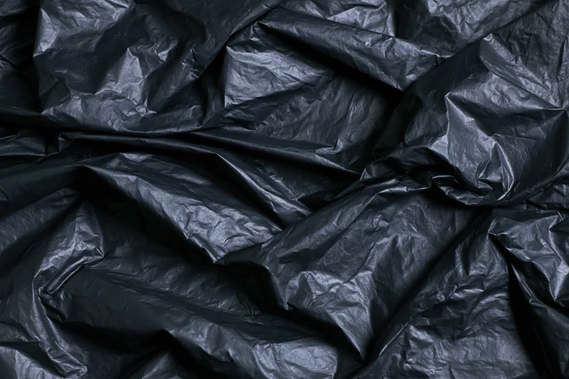 Close-up of heavily crumpled black plastic sheeting laid flat