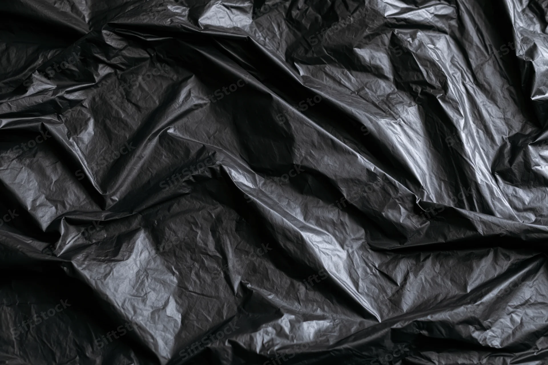 Close-up of heavily crumpled black plastic sheeting laid flat