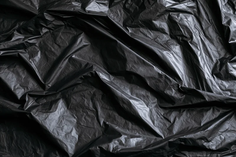 Close-up of heavily crumpled black plastic sheeting laid flat