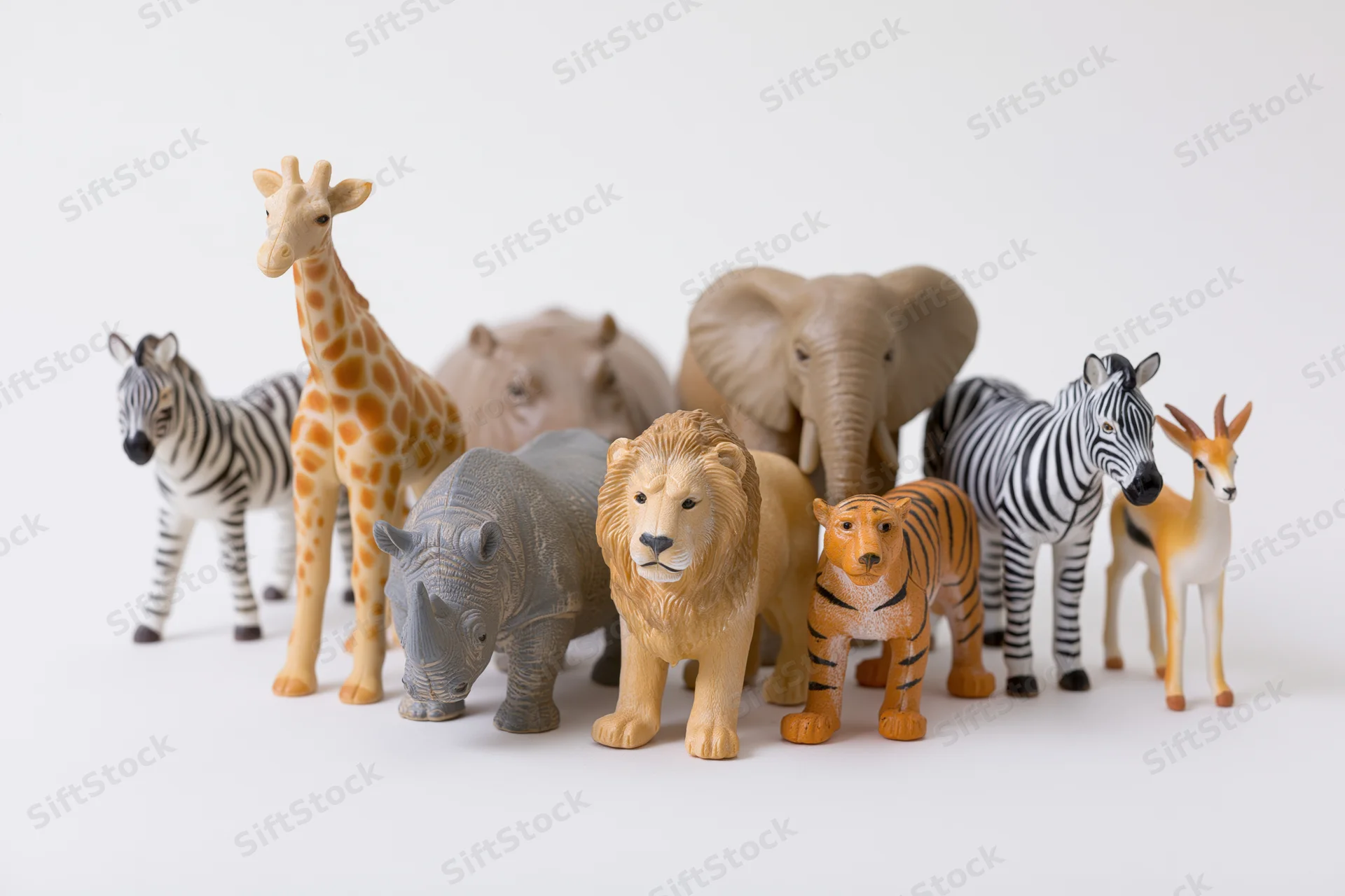 Plastic safari animal figurines arranged in a group on a white surface