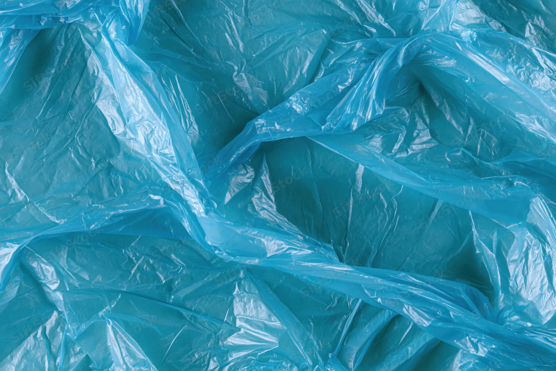 Crumpled translucent blue plastic bag spread flat filling the frame