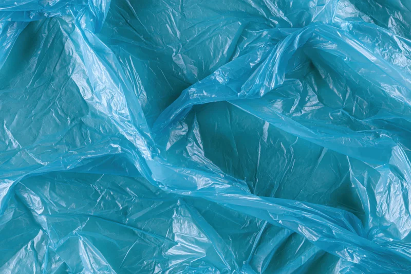 Crumpled translucent blue plastic bag spread flat filling the frame