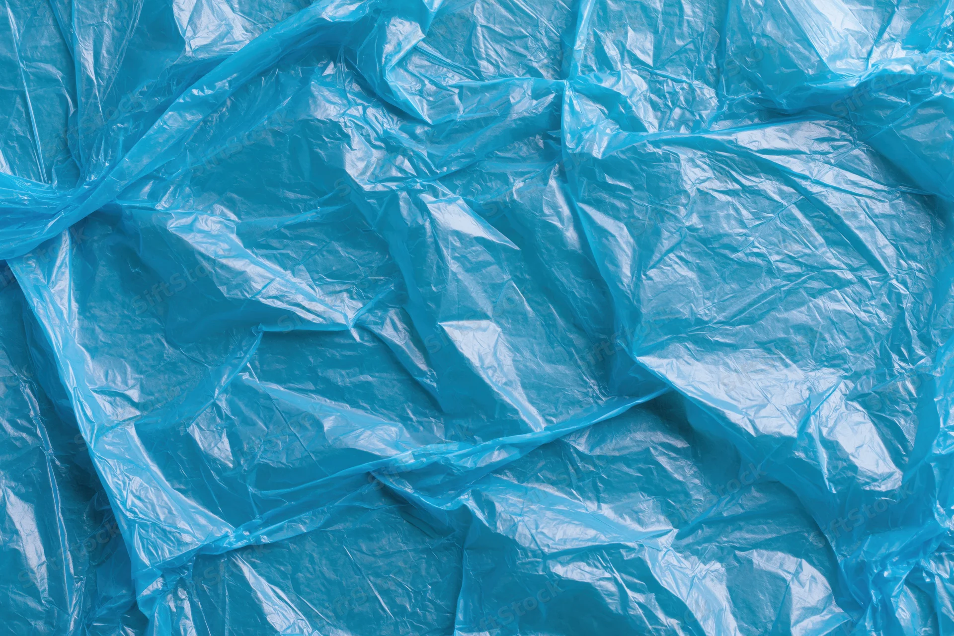 Crumpled translucent blue plastic bag spread flat filling the frame