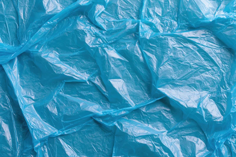 Crumpled translucent blue plastic bag spread flat filling the frame