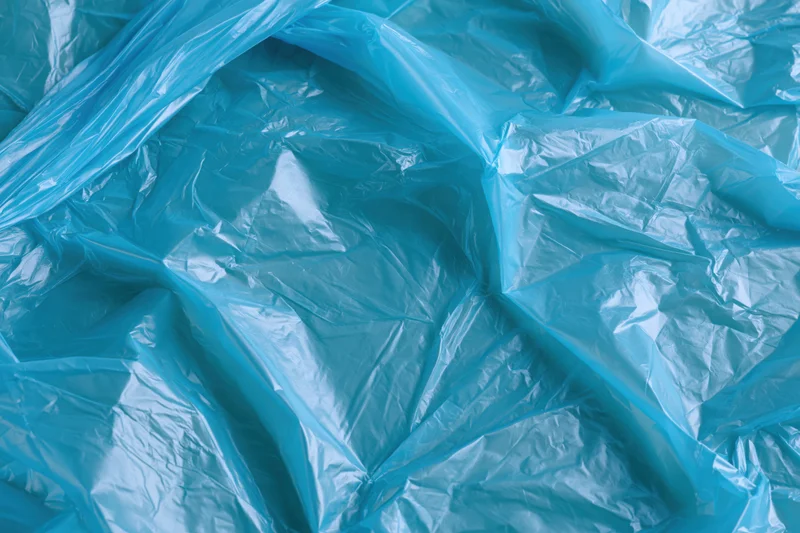 Crumpled translucent blue plastic bag spread flat filling the frame