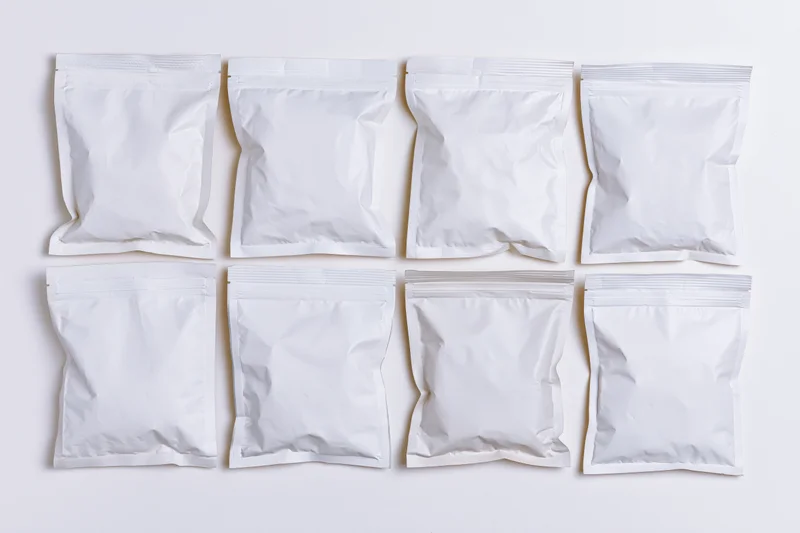 Eight blank white resealable snack pouches arranged in two rows on a white surface