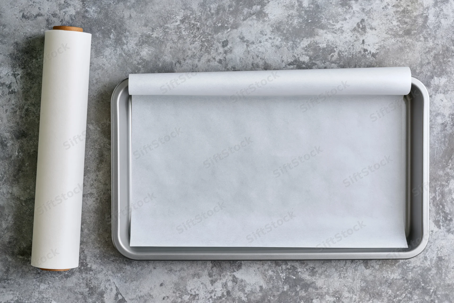 Rectangular metal baking tray lined with white parchment paper on gray countertop