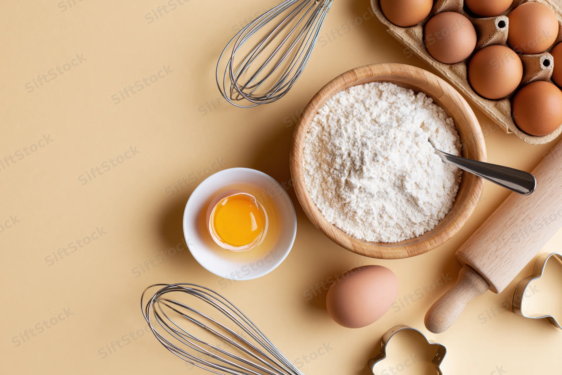 Baking ingredients and tools arranged on a warm beige surface with copyspace
