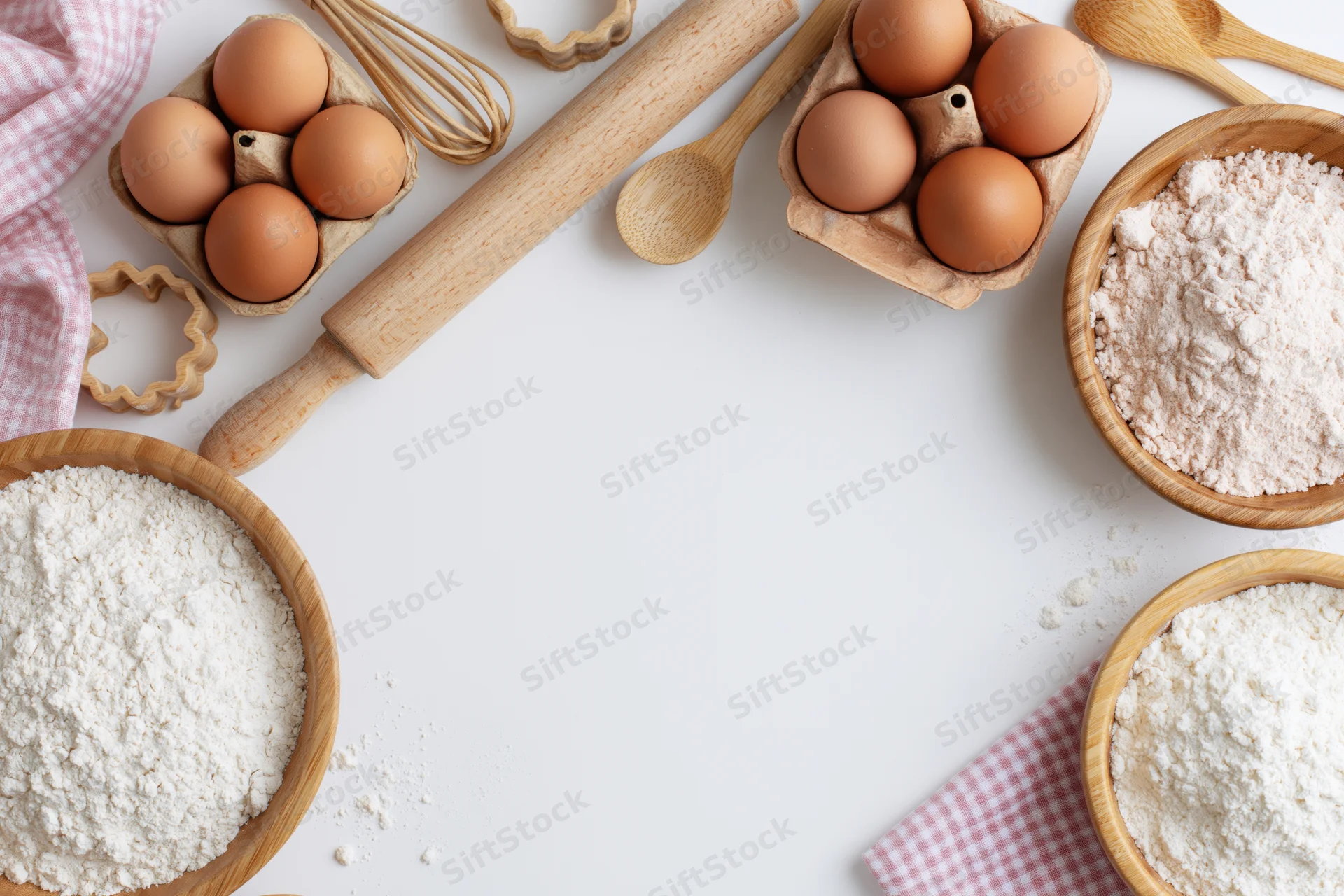 Baking ingredients arranged in a frame border on white surface with copyspace