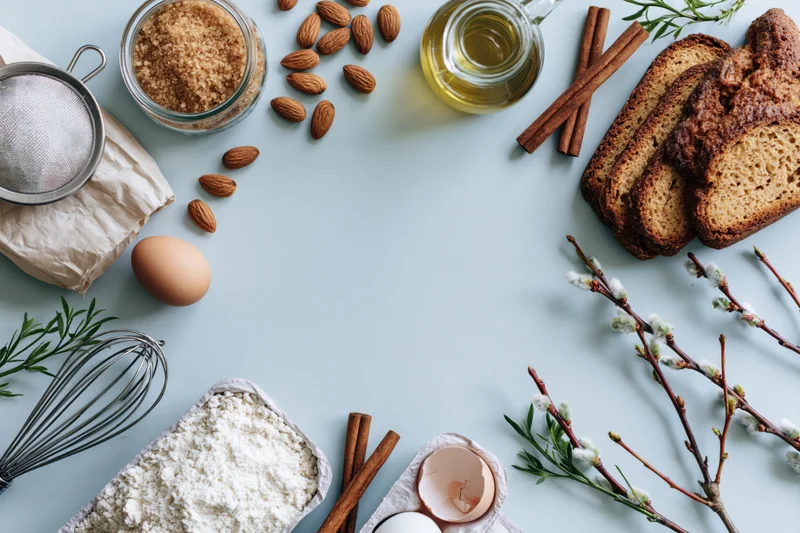 Baking ingredients arranged in a loose circle on a light blue surface with copyspace
