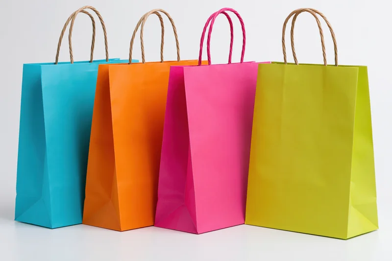 Four colorful paper shopping bags arranged in a row on a white surface