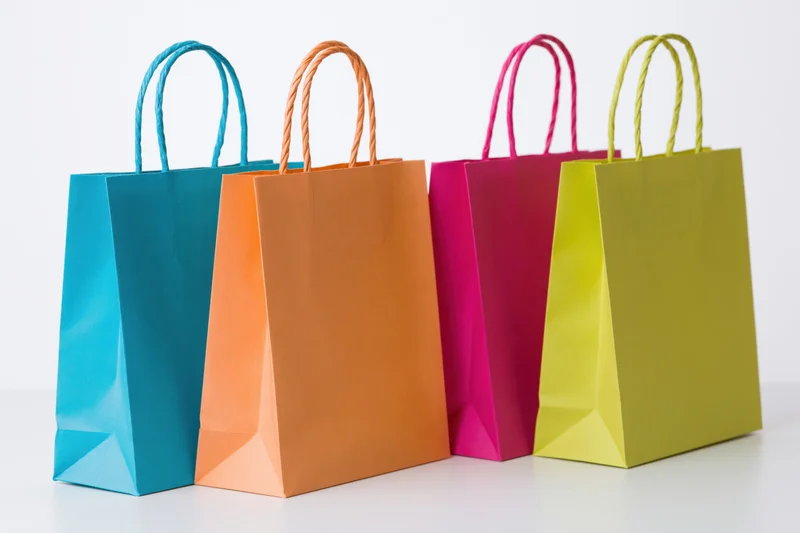 Four colorful paper shopping bags arranged in a row on a white surface