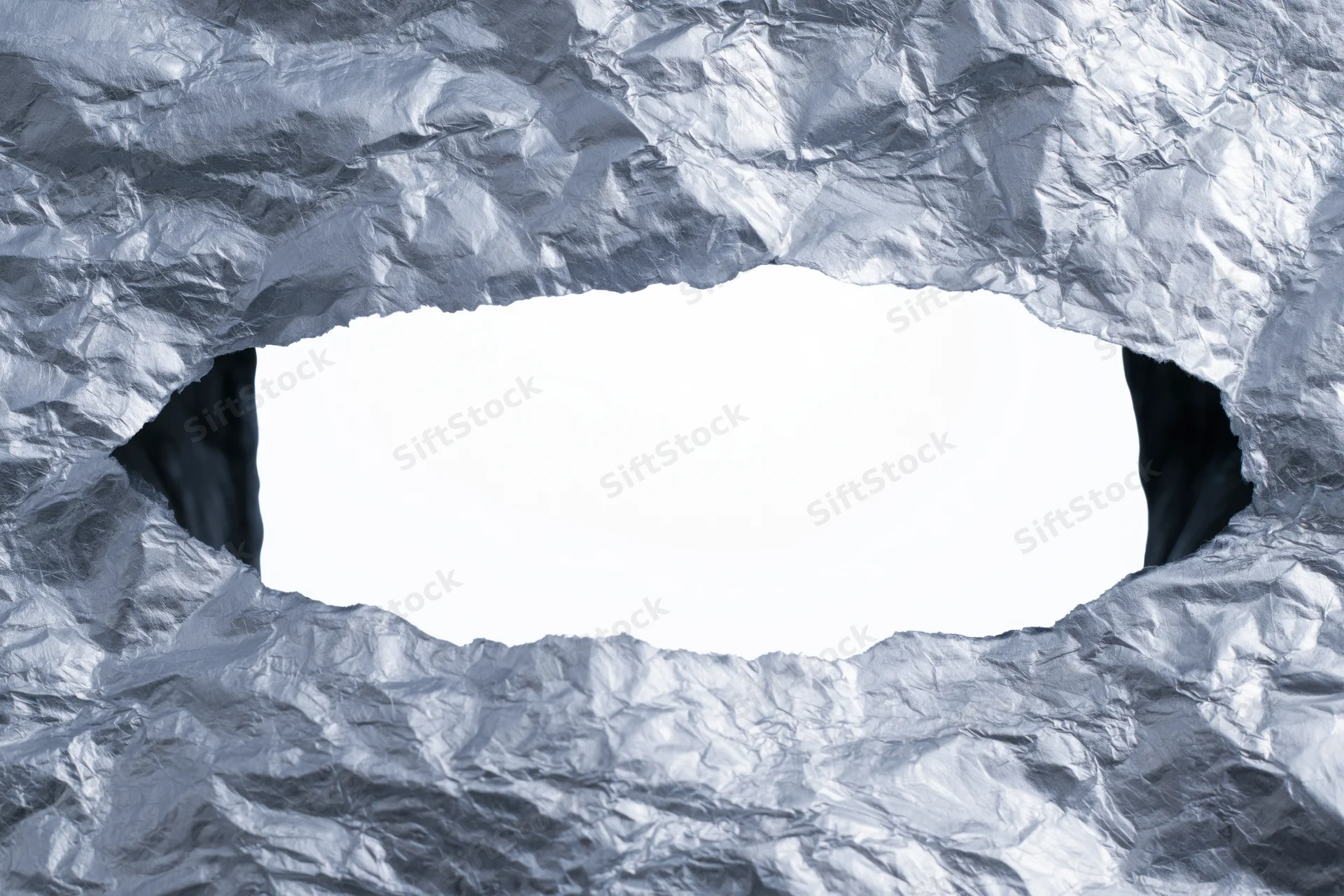 View through a torn rectangular hole in crumpled aluminum foil with white copyspace inside