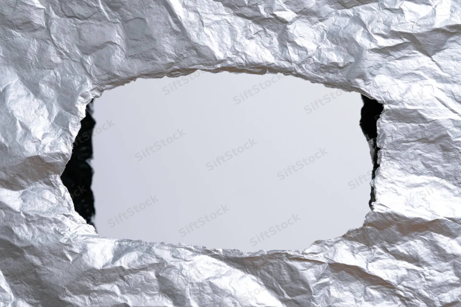 Interior view through a torn rectangular hole in crumpled white paper