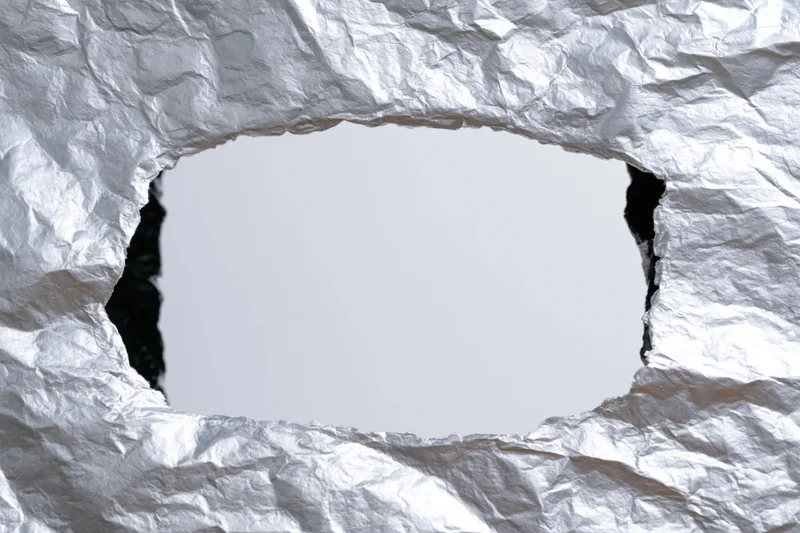 Interior view through a torn rectangular hole in crumpled white paper