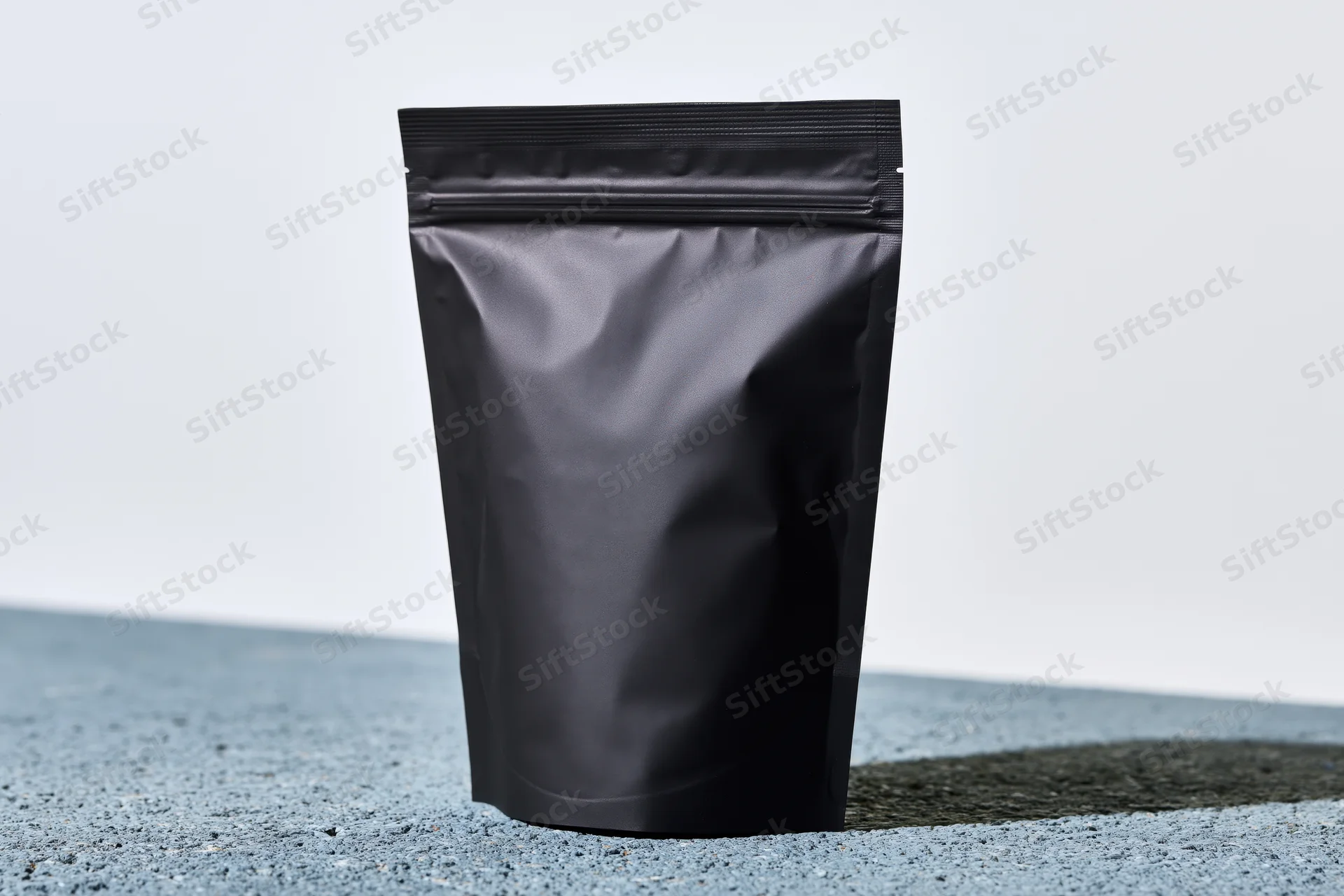 Matte black standup coffee pouch with zip closure on textured surface