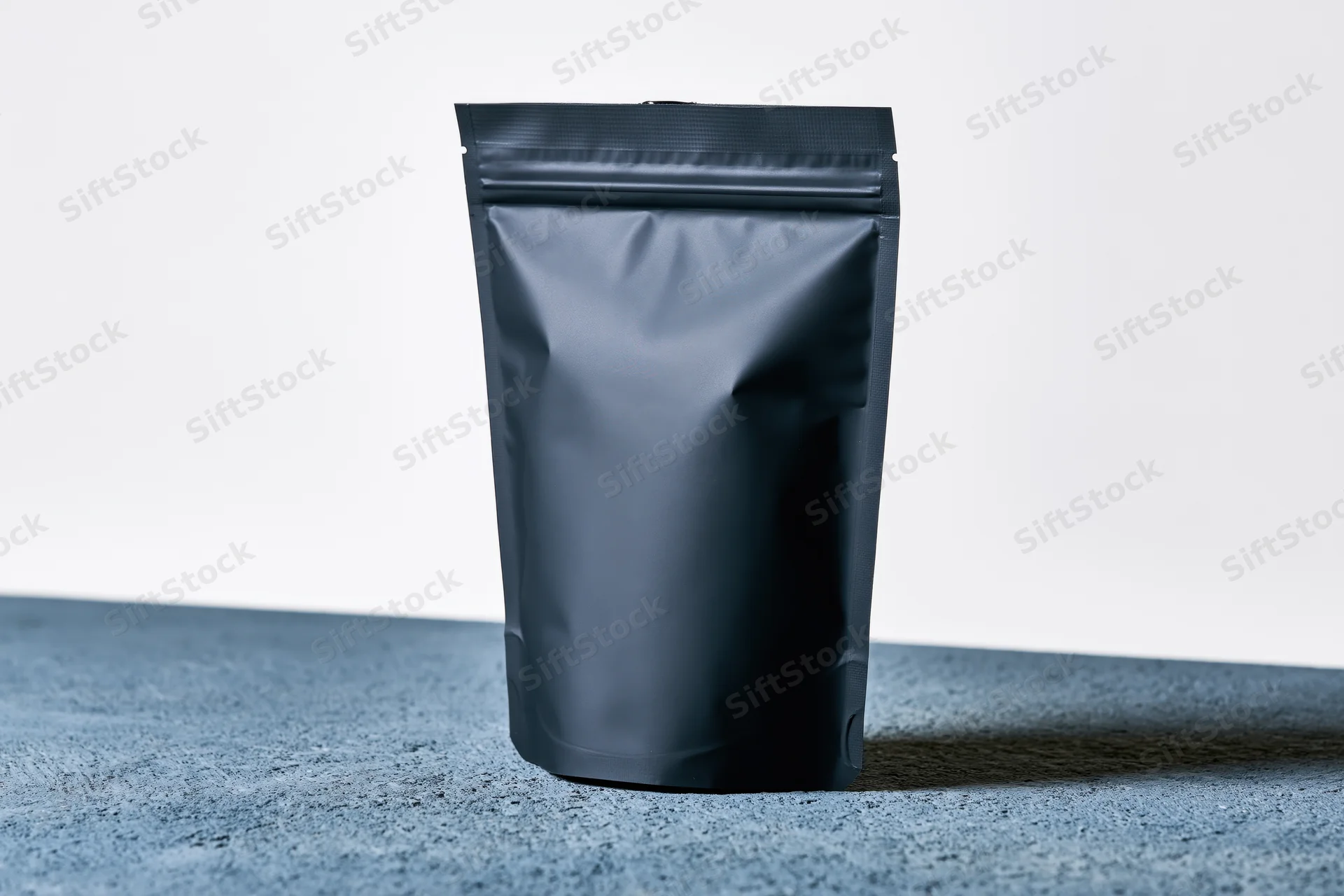 Matte black standup coffee pouch with zip closure on concrete surface