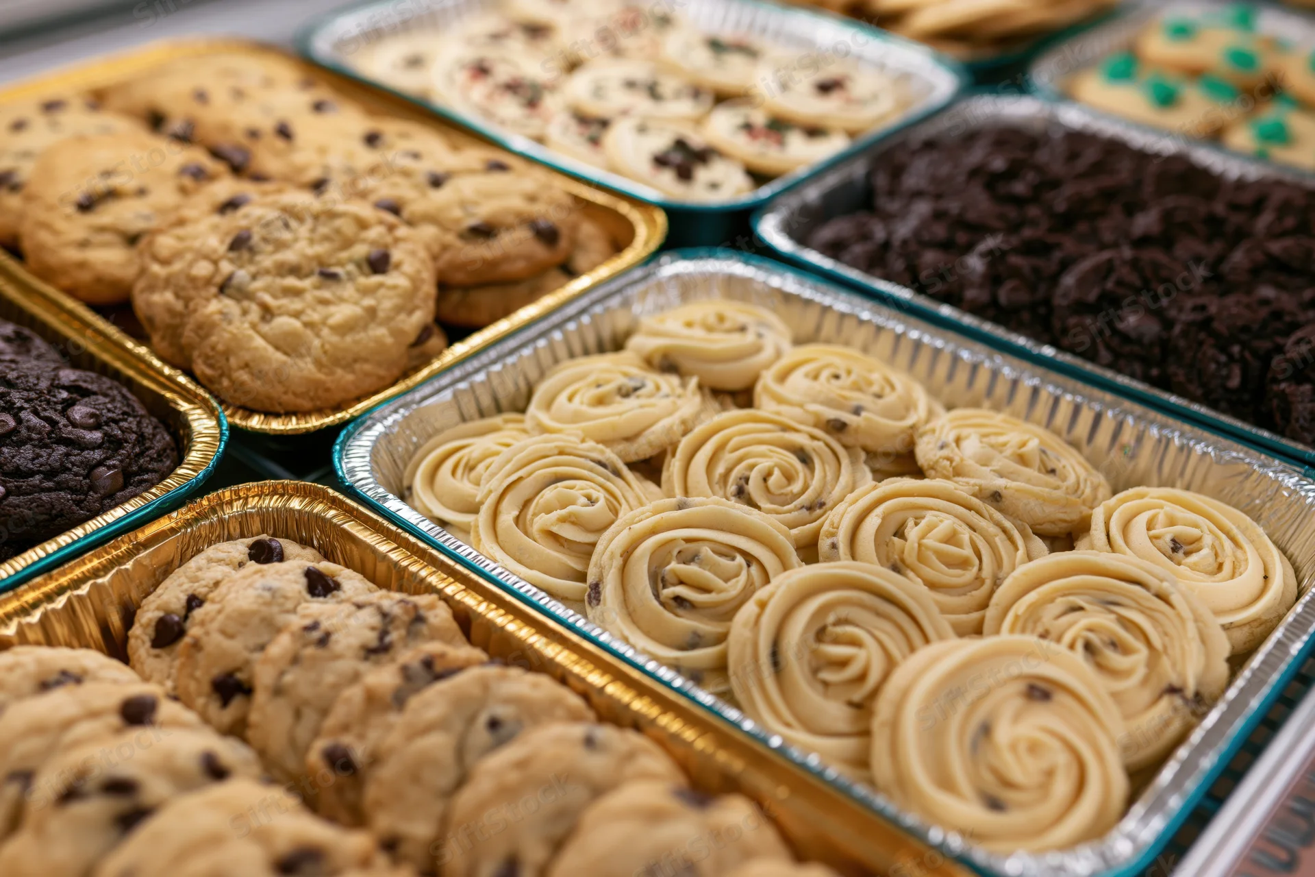 Assorted bakery cookies in aluminum trays arranged for display at a community event