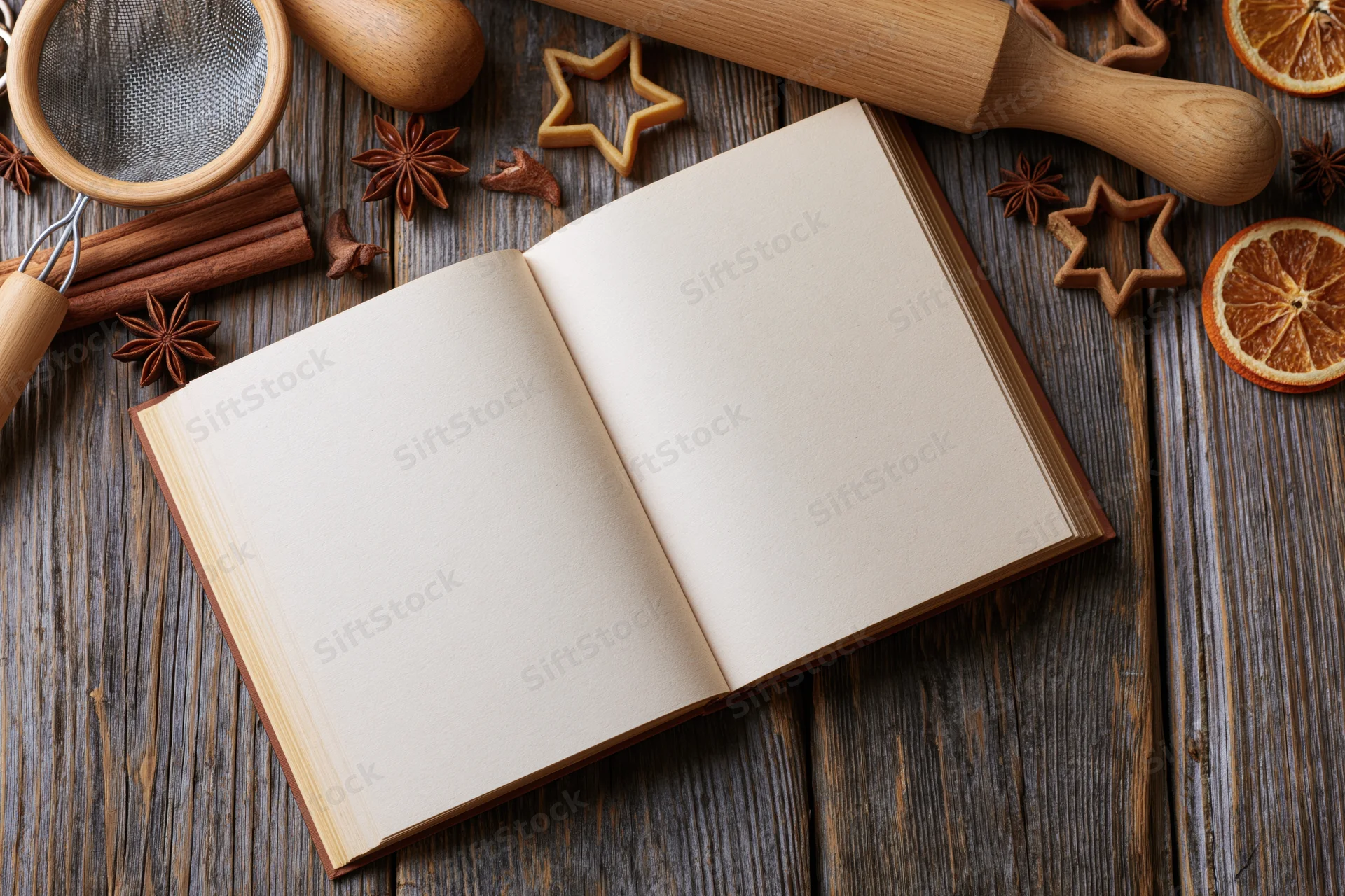 Open blank recipe book on weathered dark wood table surrounded by baking tools and spices