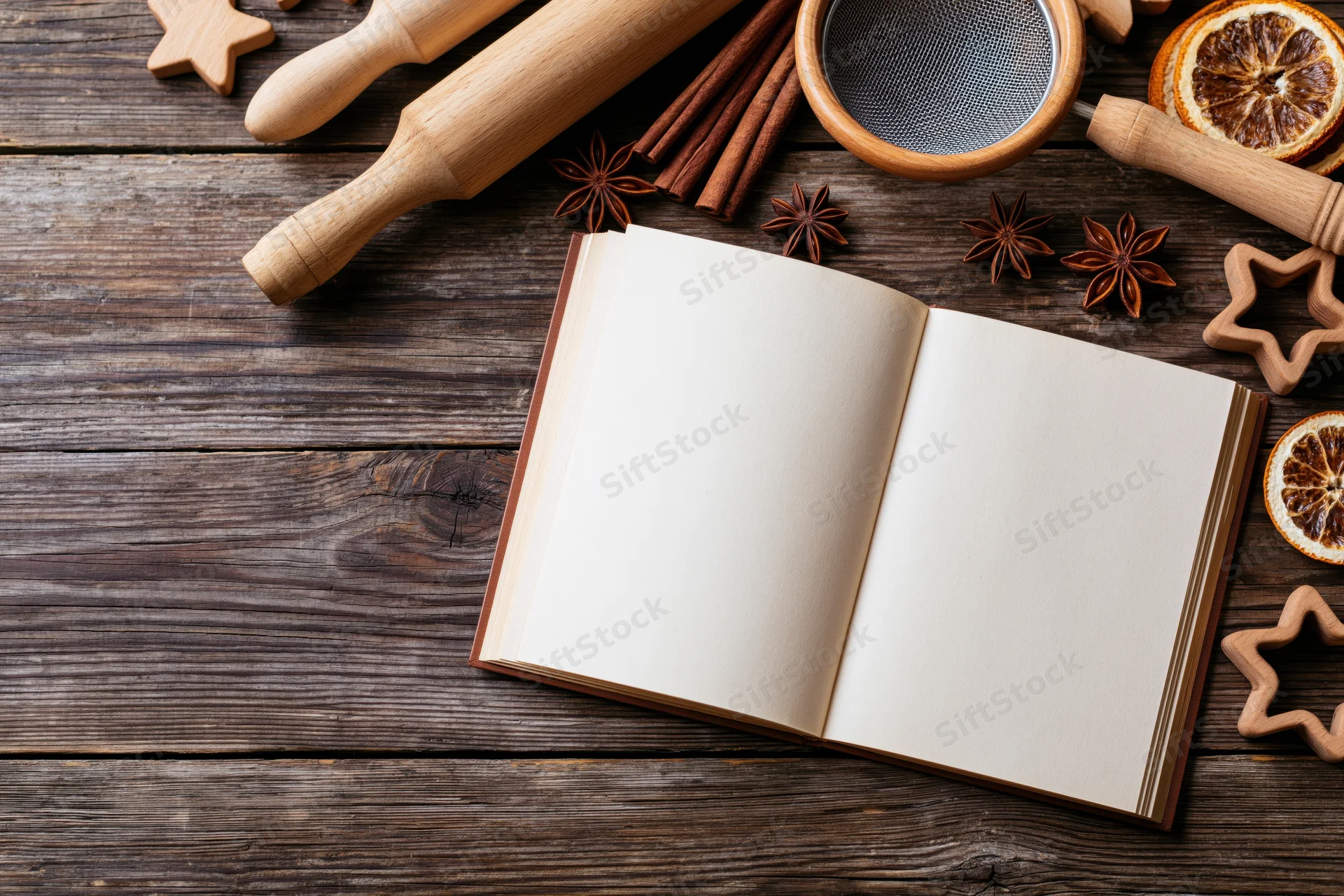 Open blank recipe book on dark wooden table surrounded by baking tools and spices