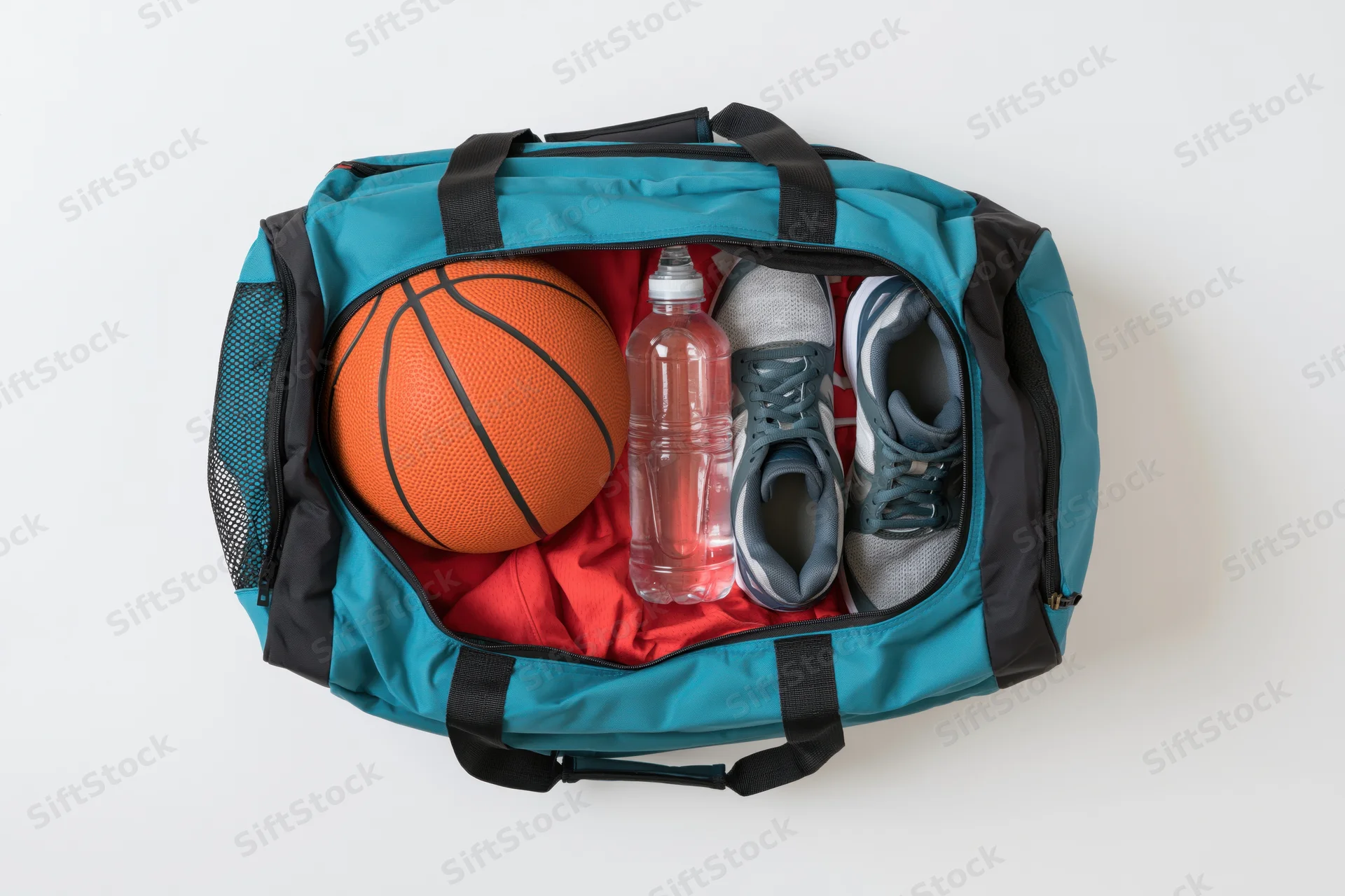 Open teal and black sports duffel bag packed with basketball, sneakers, water bottle, and red shirt on white background