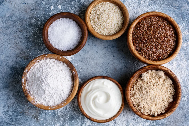 Baking ingredients arranged in a ring on a textured surface in overhead flat lay view