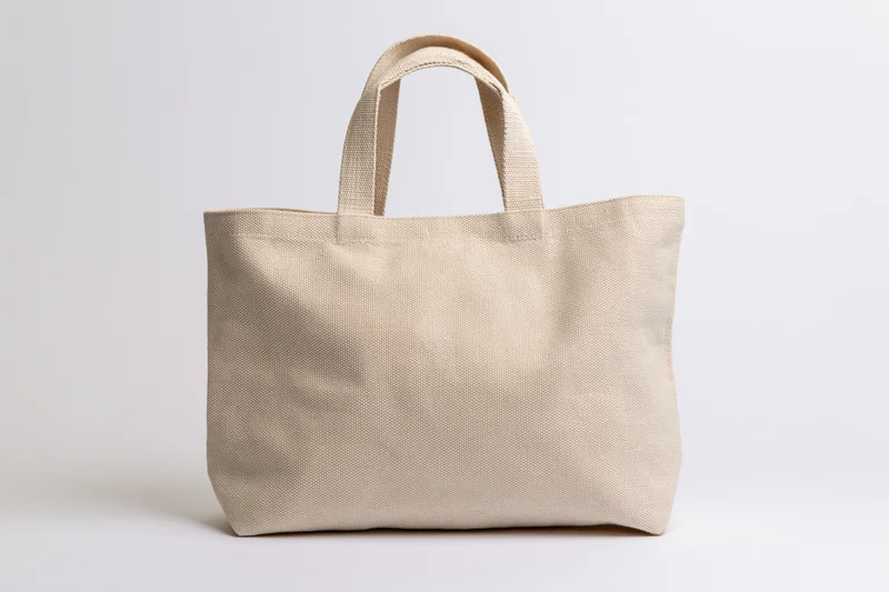 Plain natural canvas tote bag with two handles on white background