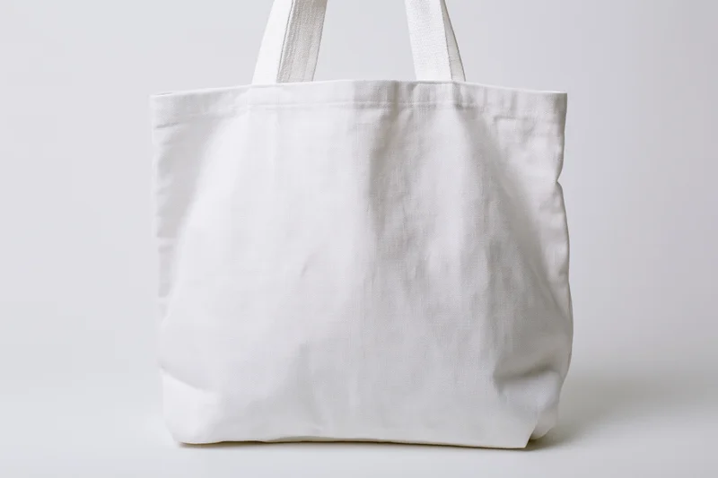 Plain white canvas tote bag with short handles on white background