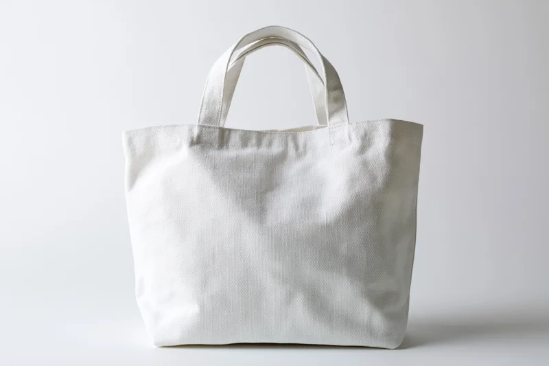 Plain white canvas tote bag with short handles on white background