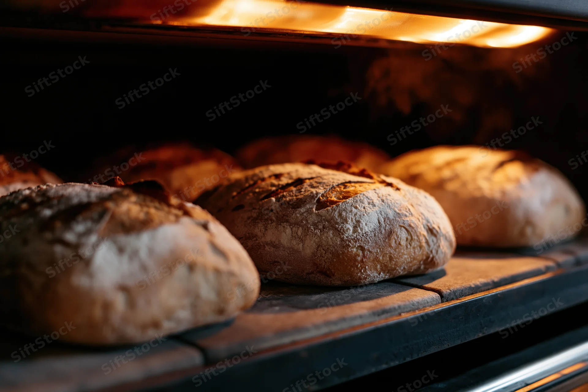 Sourdough loaves baking on a stone deck inside an oven