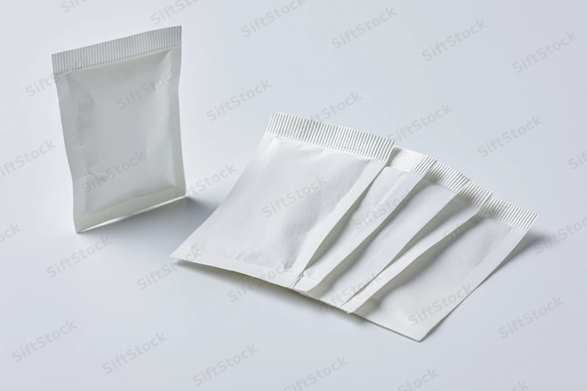 White foil sachet packets arranged on plain surface for product display