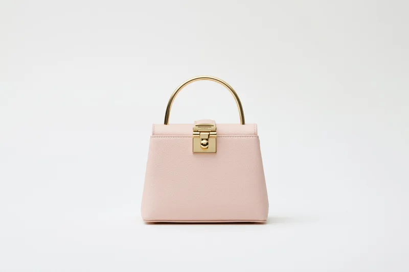 Small structured blush handbag with gold hardware on white background