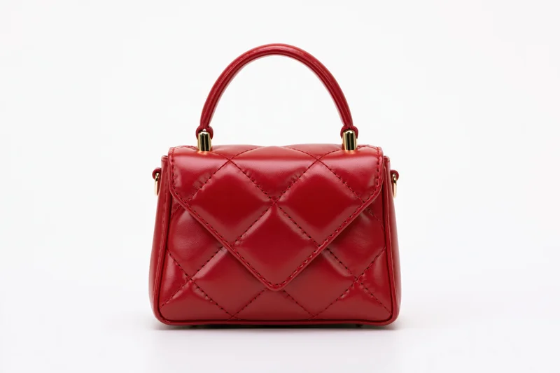 Small structured red leather handbag with quilted diamond stitching and gold hardware on white background